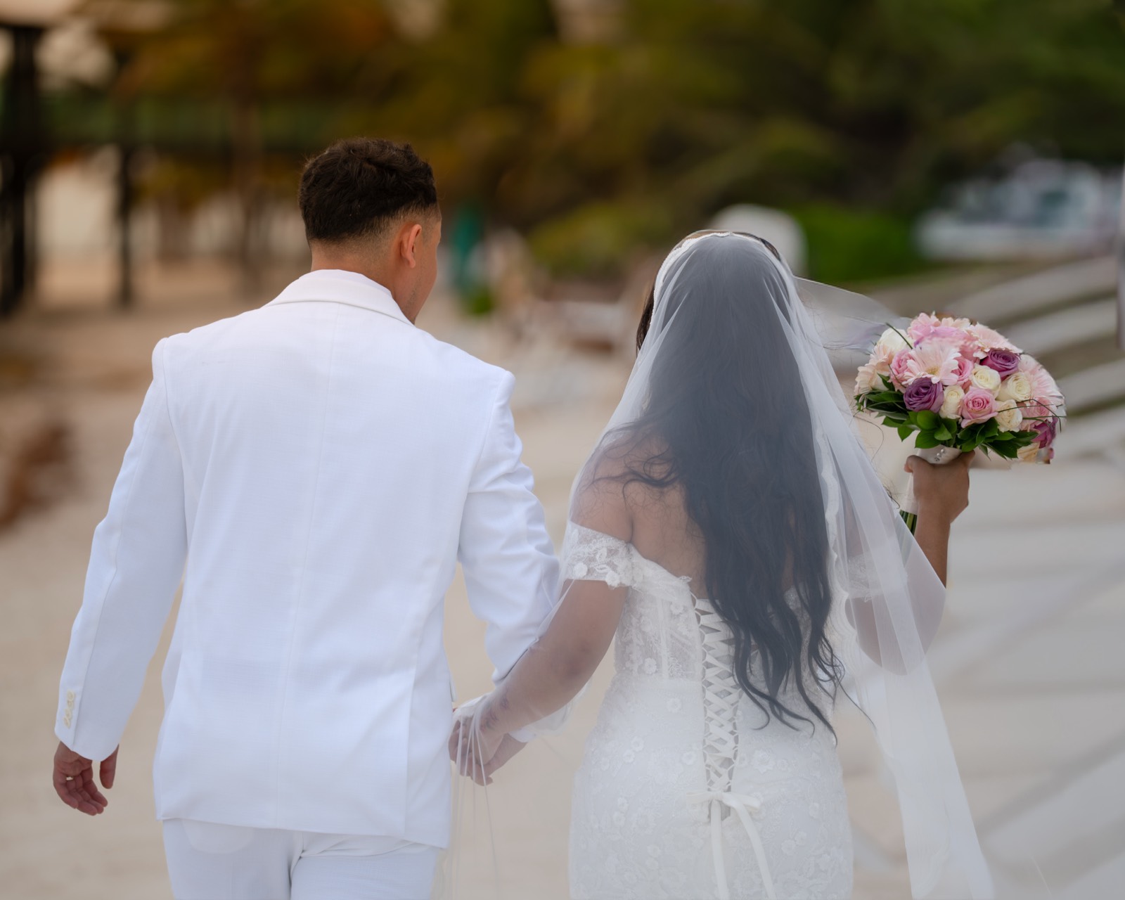 Novios caminando de la mano hacia el mar