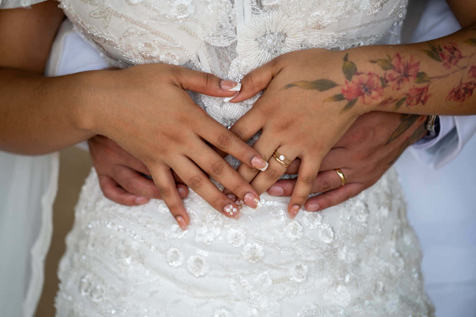Manos de los novios con sus anillos sobre el vestido