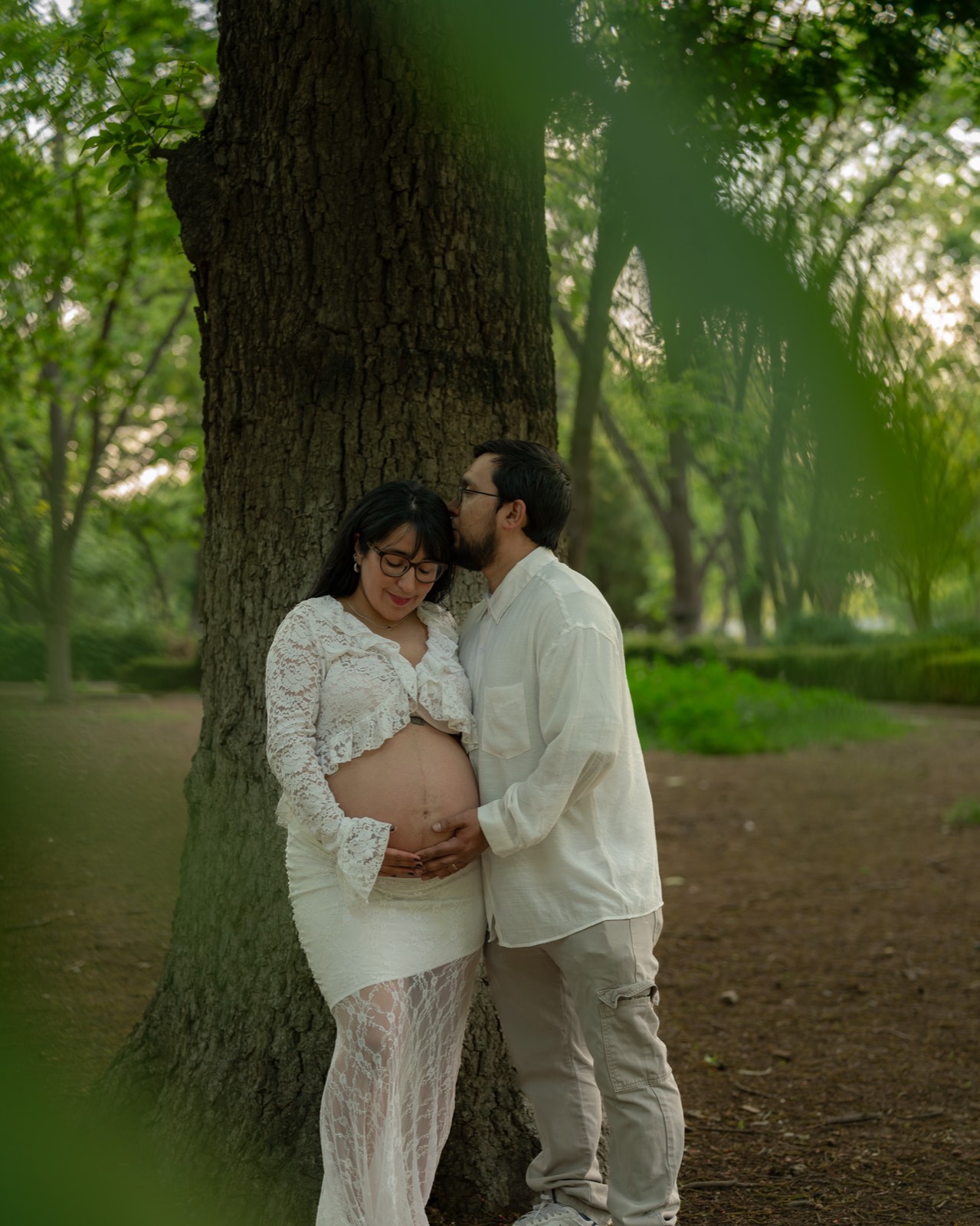 Pareja en sesión de maternidad junto a un árbol